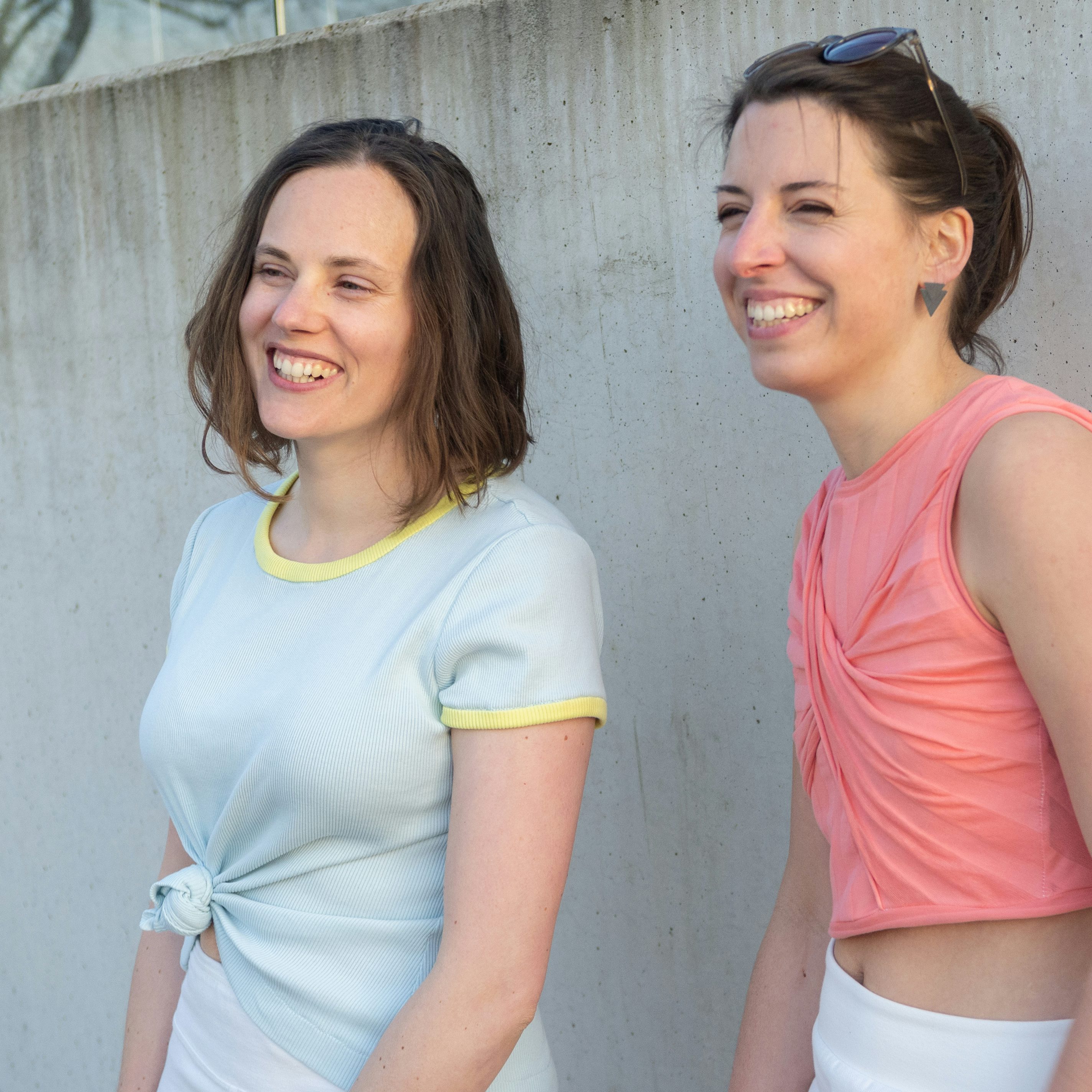 Zwei lachende Frauen in Tops in Pastellfarben. 